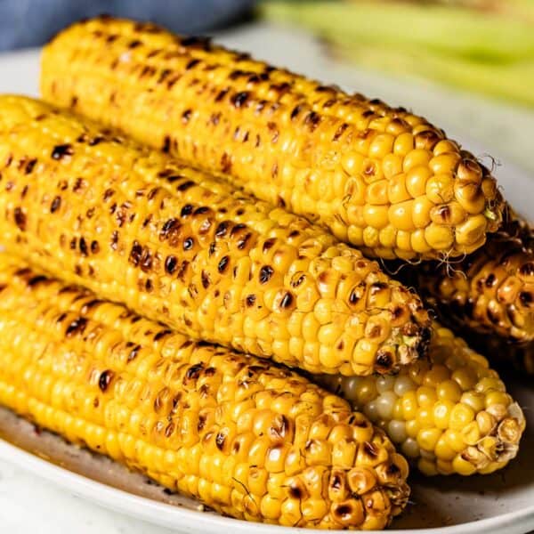 Several ears of frilled corn on the cob on a plate.