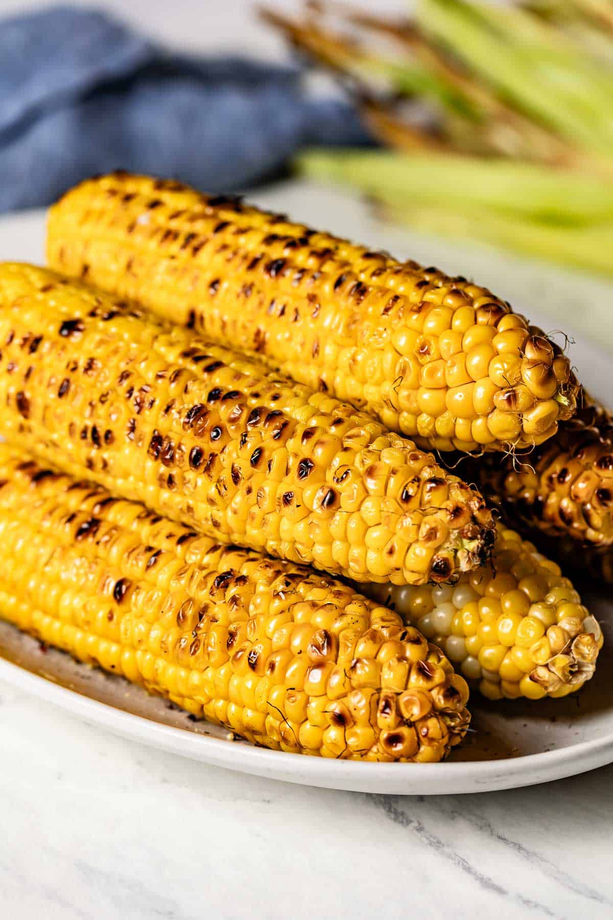 Several ears of frilled corn on the cob on a plate.