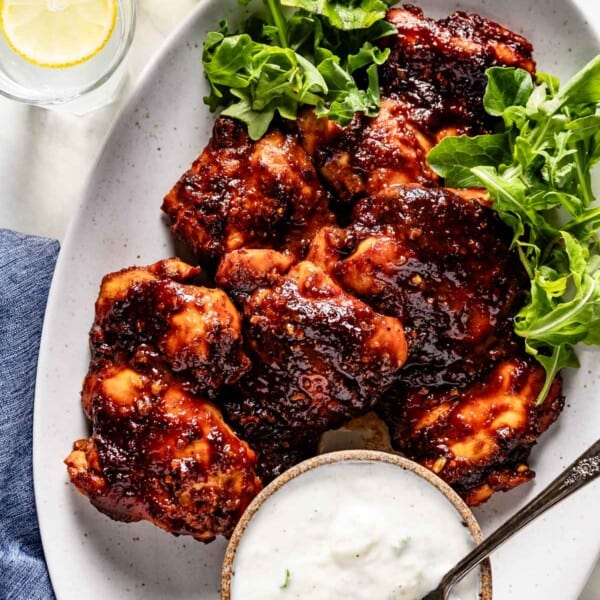 Hot honey harissa chicken on a plate with tzatziki sauce on the side.