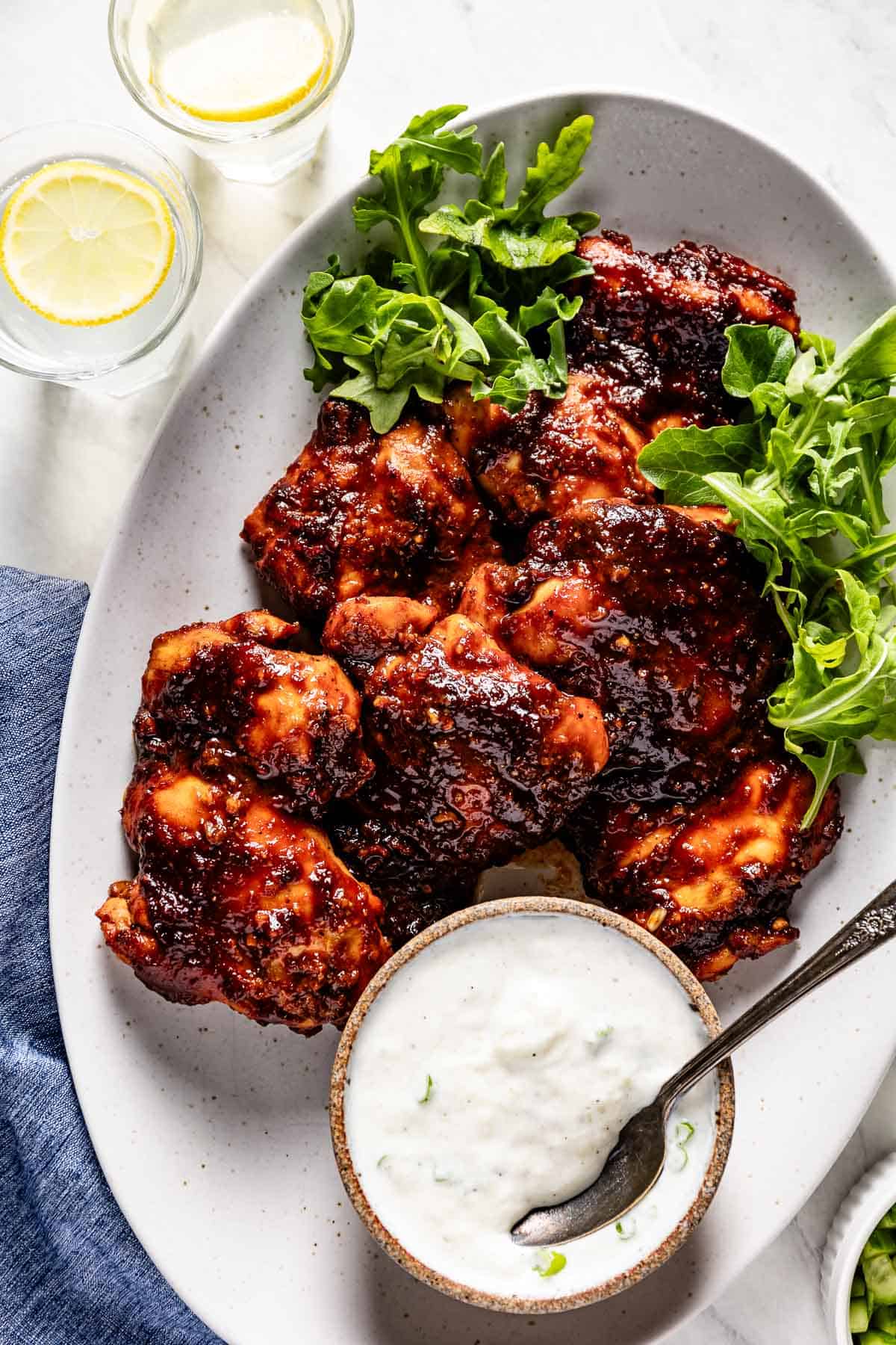 Hot honey harissa chicken on a plate with tzatziki sauce on the side.