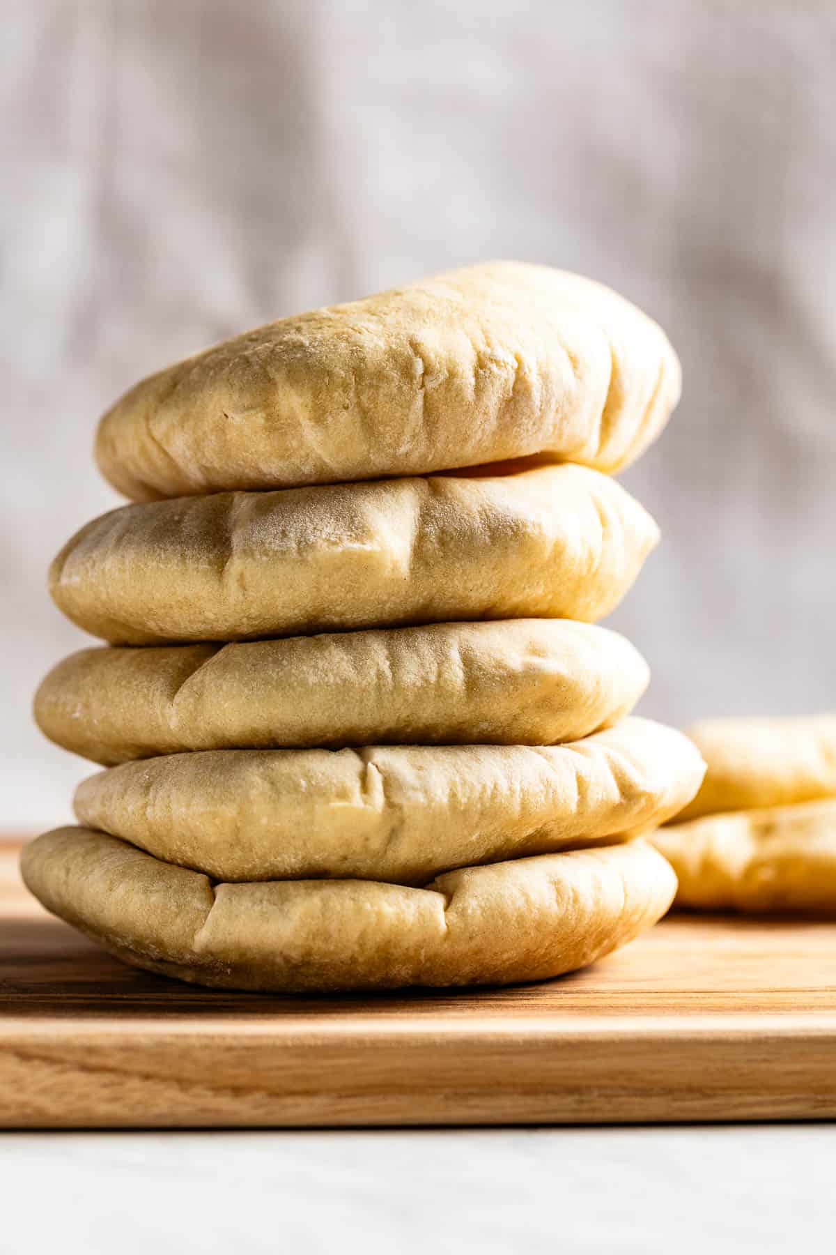 Pita bread loaves on a wooden cutting board.