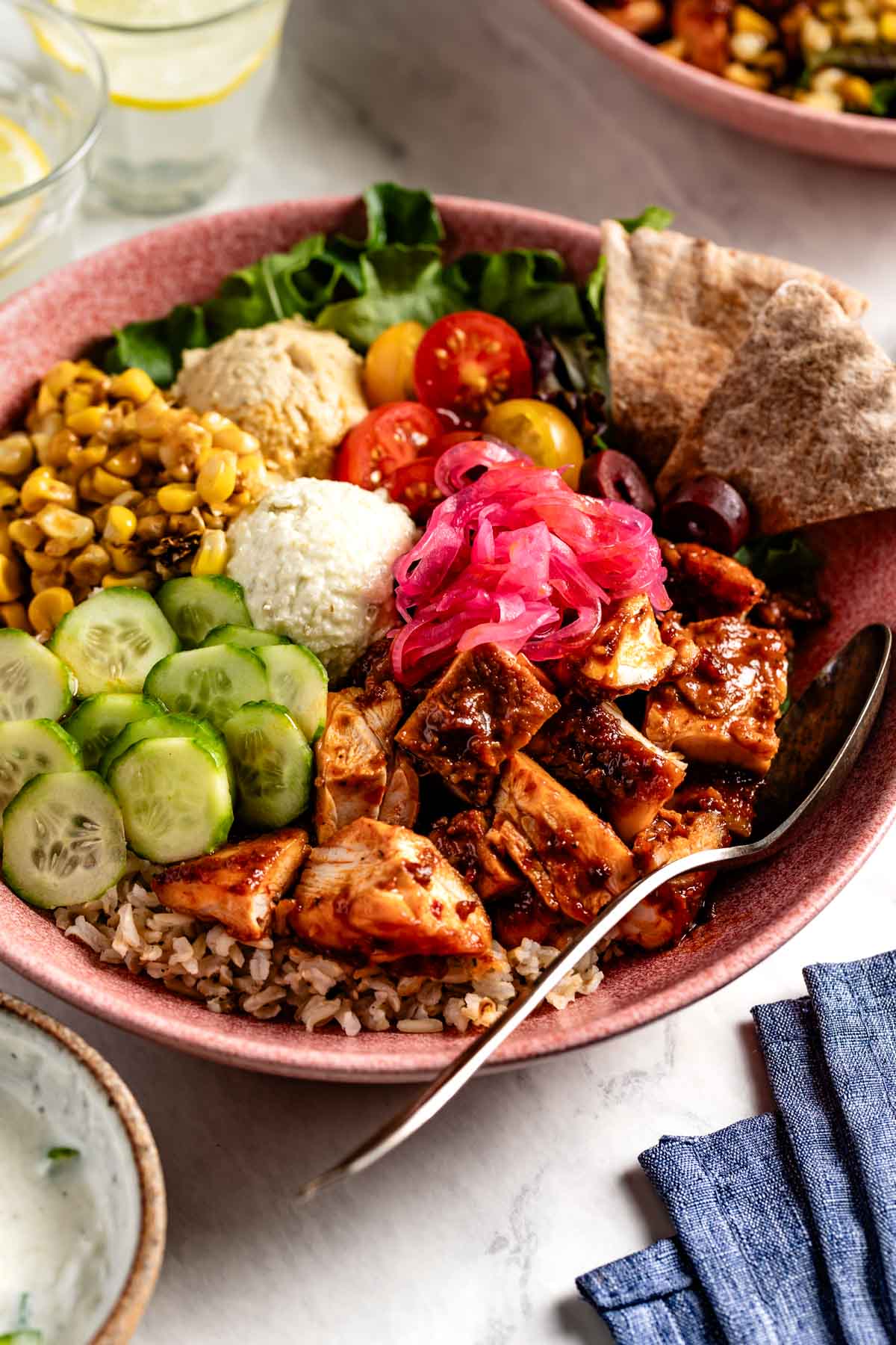 CAVA style bowl with harissa honey chicken on a plate with other toppings.