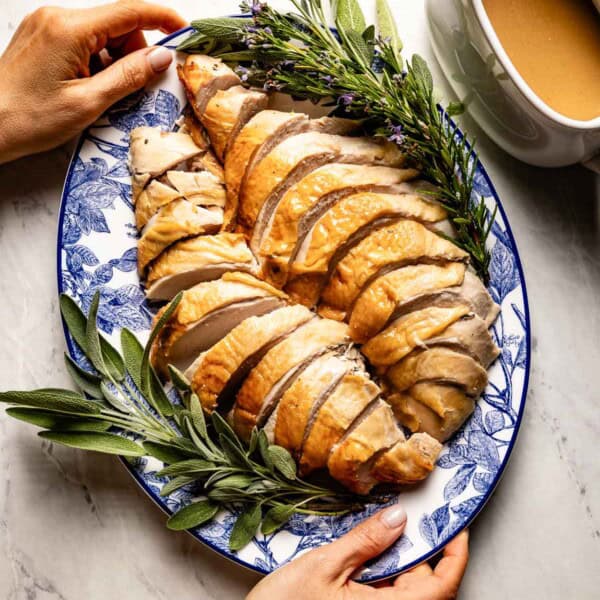 Sliced roasted turkey breast served with gravy on the side from the top view.
