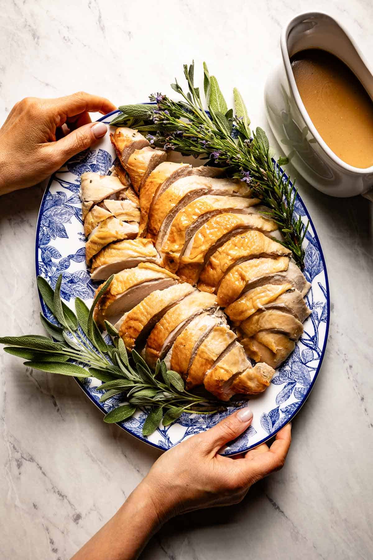 Sliced roasted turkey breast served with gravy on the side from the top view.