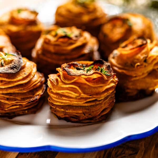 Sweet potato stacks garnished with thyme on a plate.