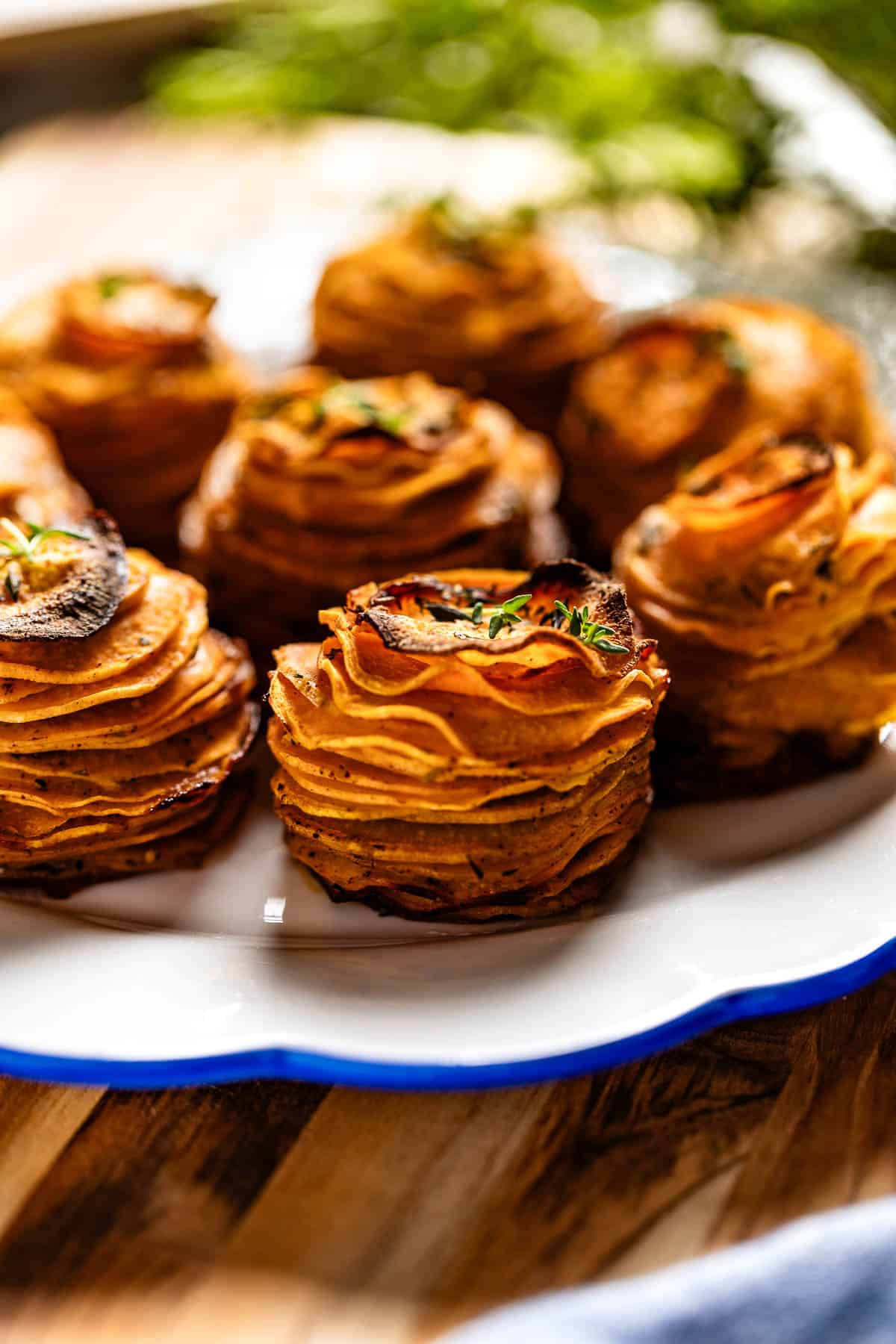 Sweet potato stacks garnished with thyme on a plate.