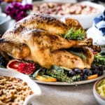 Herb crusted turkey roast garnished with fruit and placed on a table.