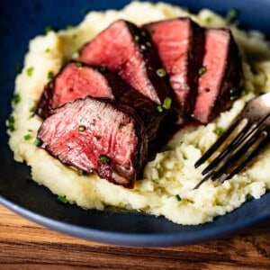 Reverse seared filet steak sliced and served on a bed of mashed potatoes.