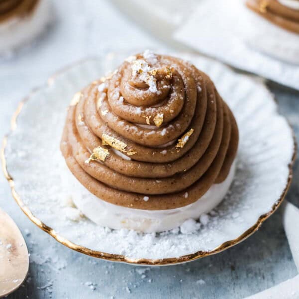 Mont Blanc dessert on a plate decorated with powdered sugar and edible gold leaf.