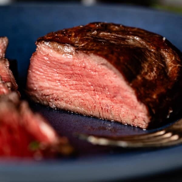 Reverse sear filet mignon cut on a plate with a fork next to it.