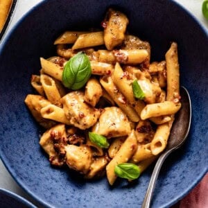 Marry me chicken pasta in a bowl garnished with basil leaves.