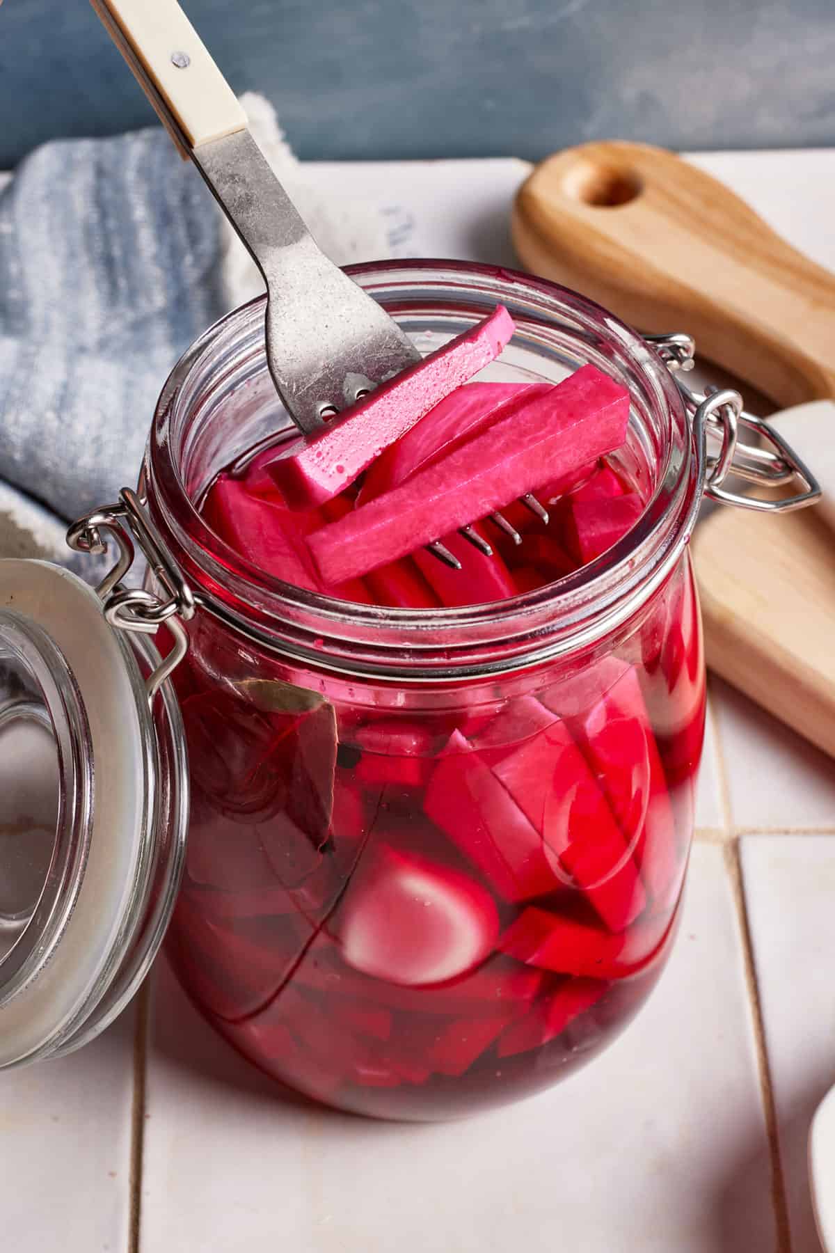 Middle Eastern pickled turnips in a jar with a few of them held in a fork.