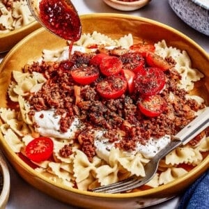 Turkish pasta being drizzled with the sauce.