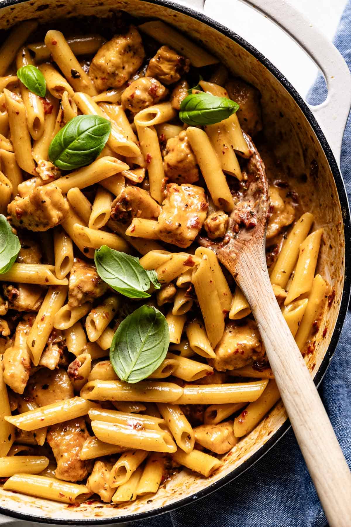 One pan marry me chicken recipe with pasta garnished with basil leaves in a pan.