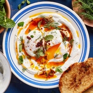 Turkish eggs recipe on a plate with bread on the side from the top view.