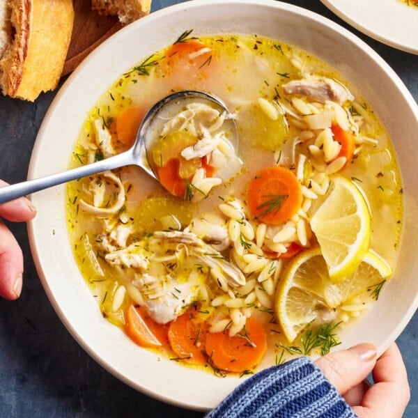 Chicken orzo soup in a bowl garnished with lemon from the top view.