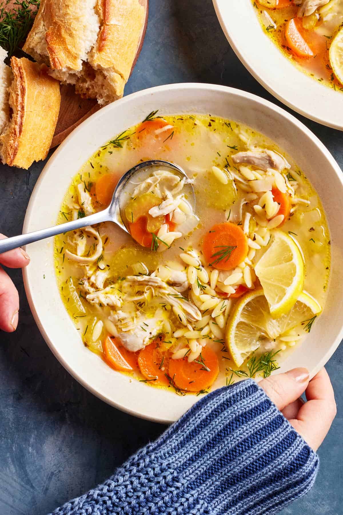 Chicken orzo soup in a bowl garnished with lemon from the top view.
