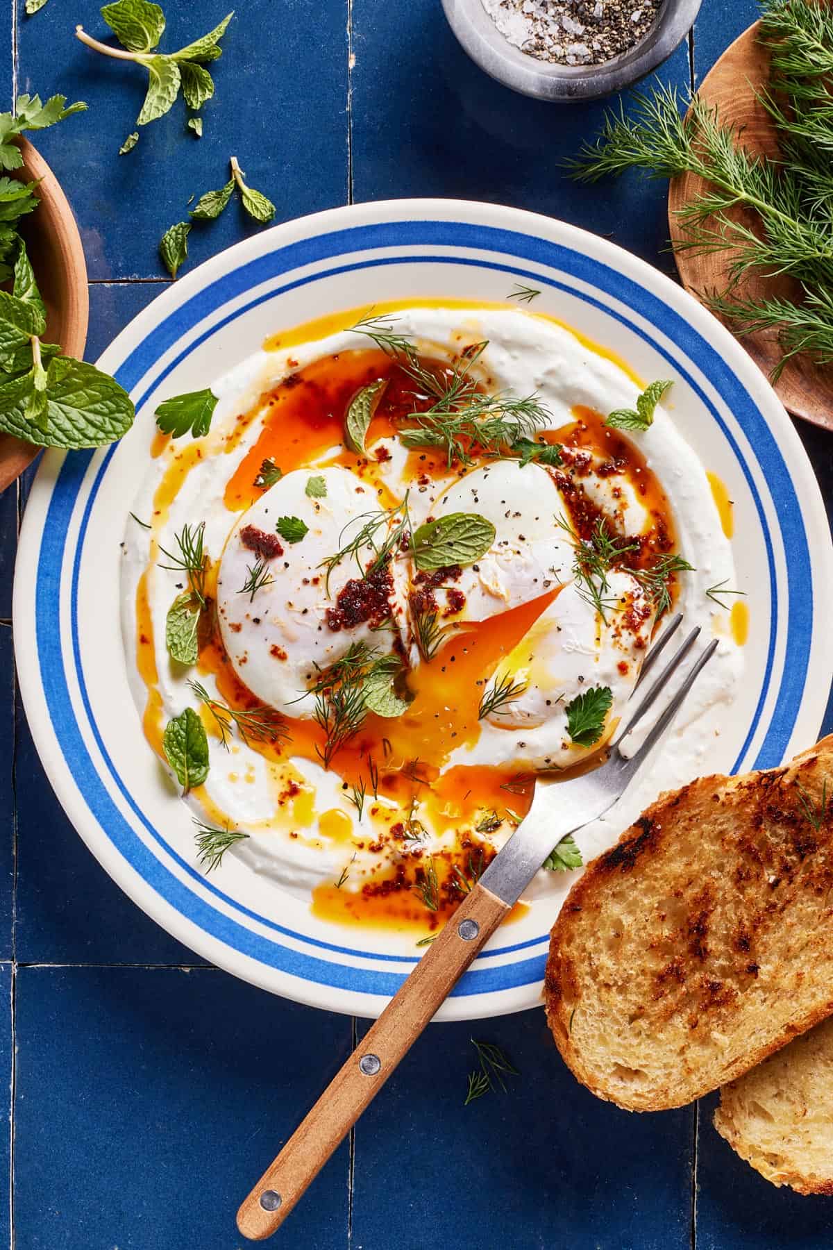 Turkish eggs with greek yogurt on a plate served with toast on the side.