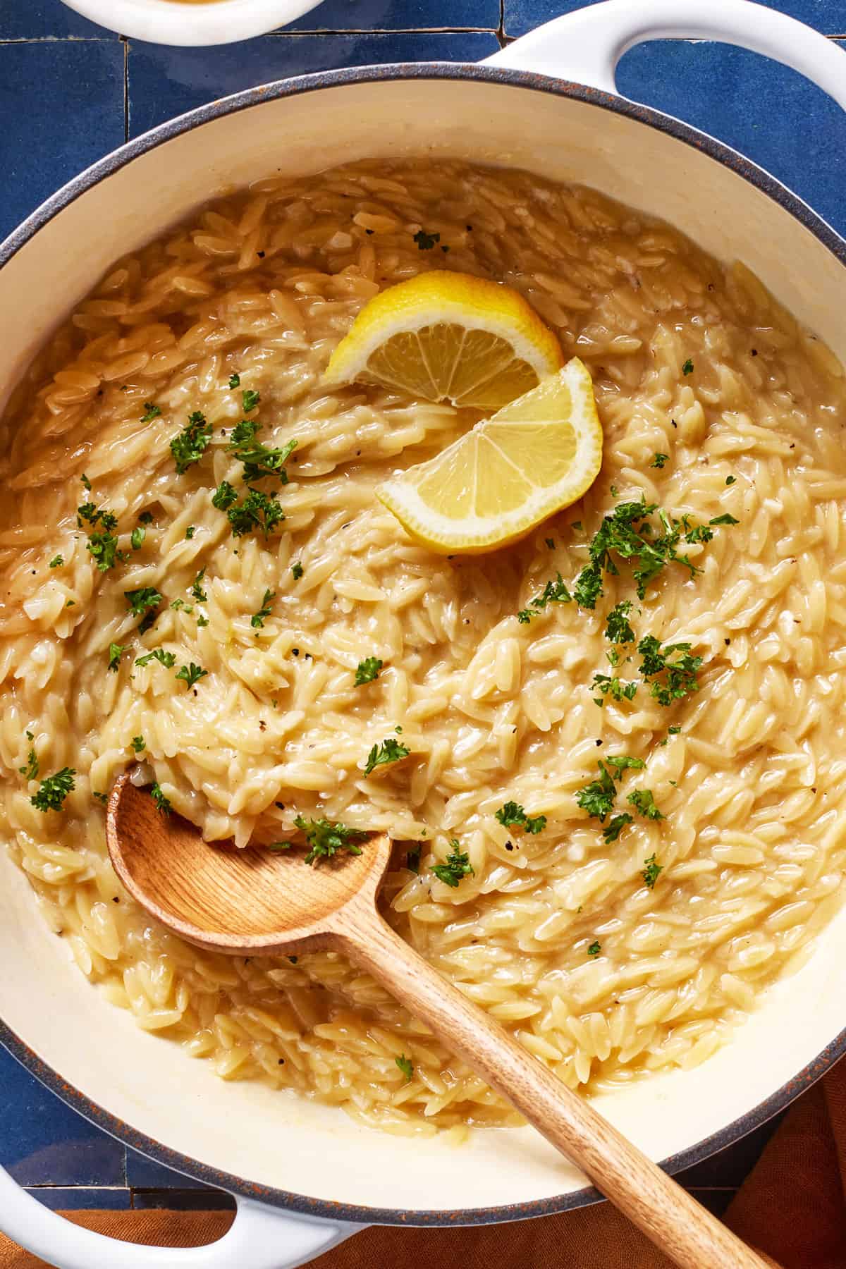 Lemon orzo garnished with lemon and parsley in a pot from the top view.