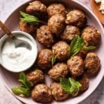 Lamb meatballs with tzatziki on a plate from the top view.