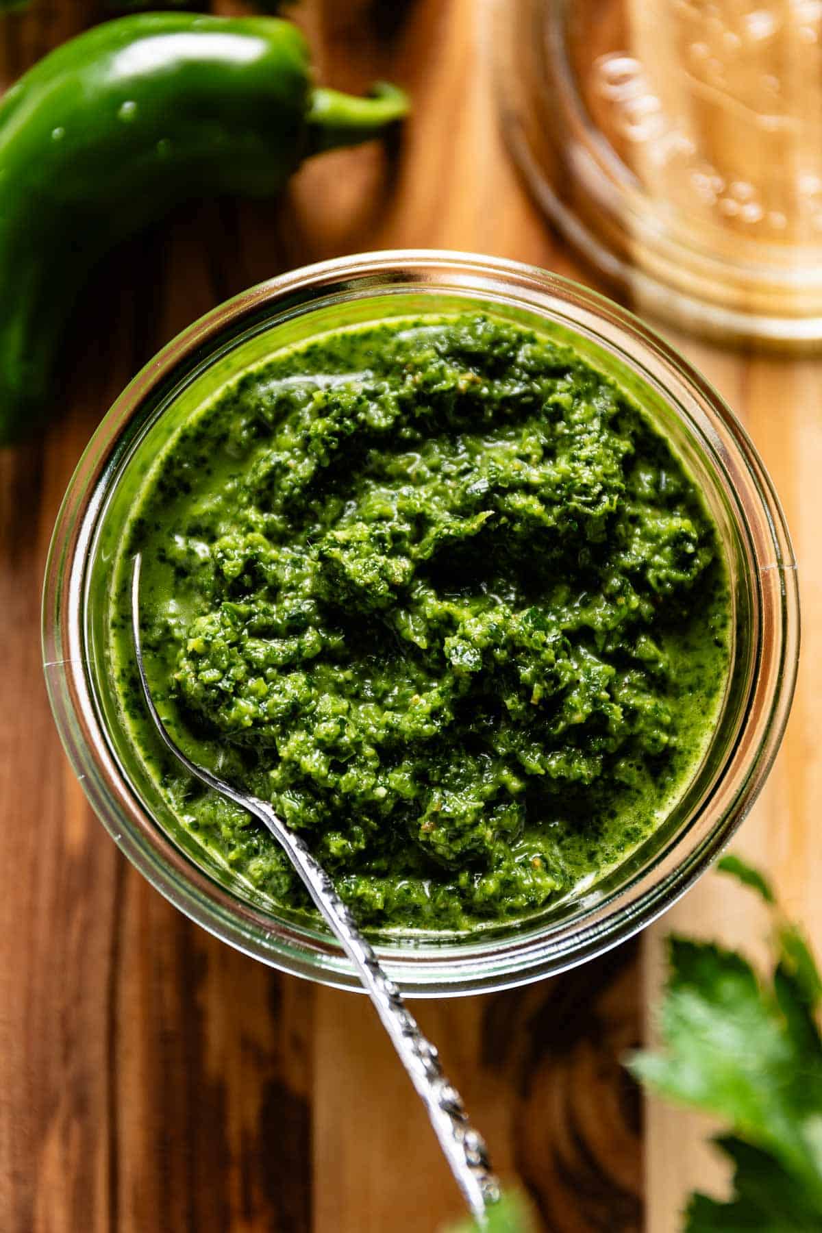Zhug sauce in a jar with a spoon on the side.