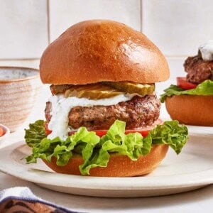 Ground lamb burger layered with tzatziki sauce from the front.