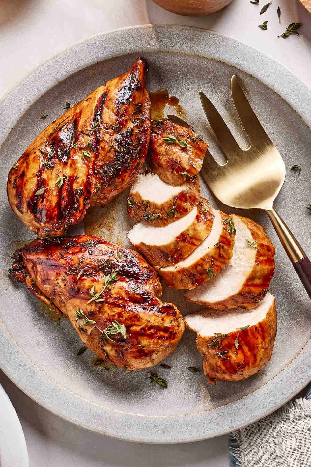 Balsamic marinated grilled chicken on a plate from the top view.