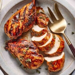 Balsamic chicken breasts sliced on a plate.