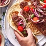 Adana kebab on a plate served over lavash.