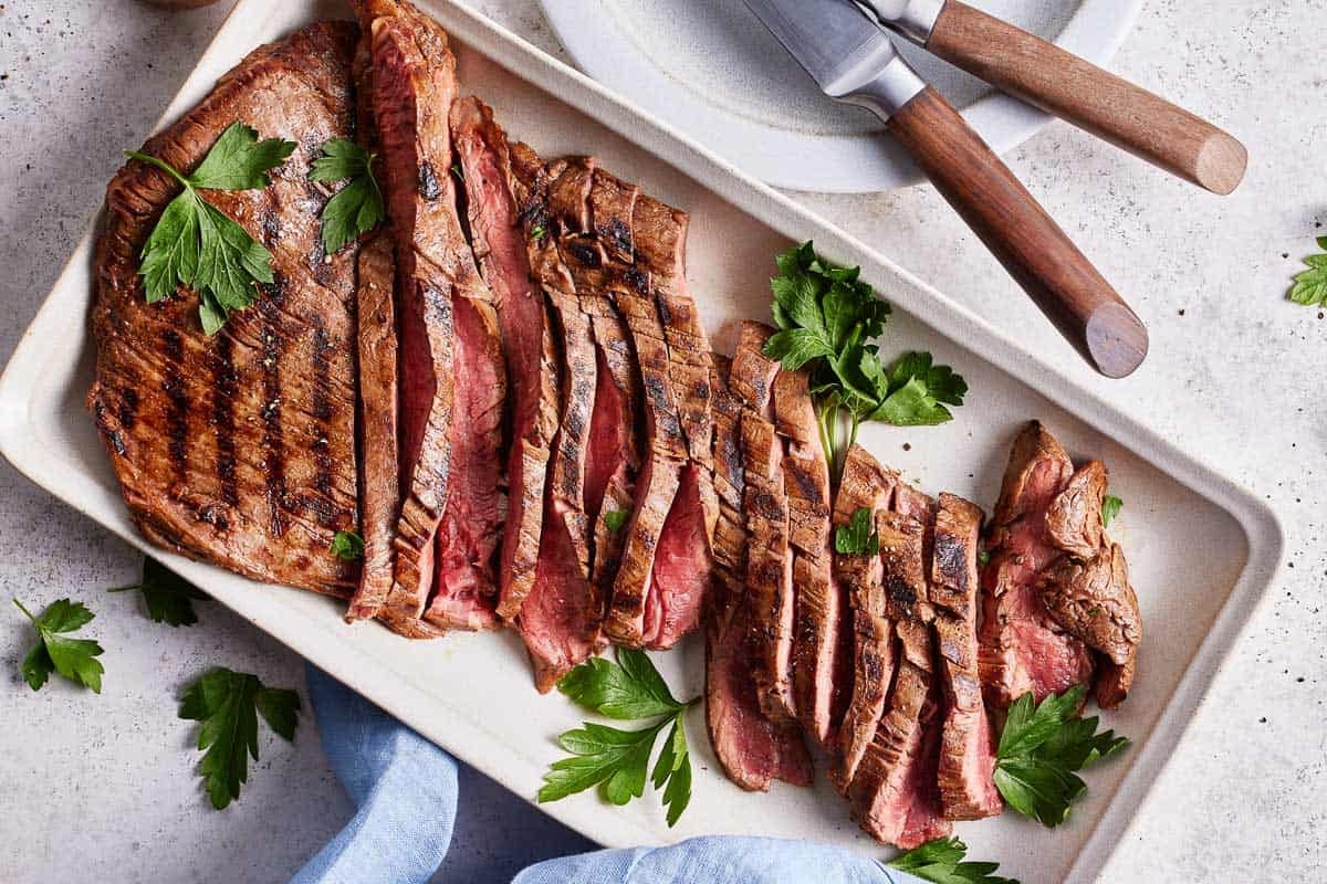 Grilled flank steak sliced on a plate.