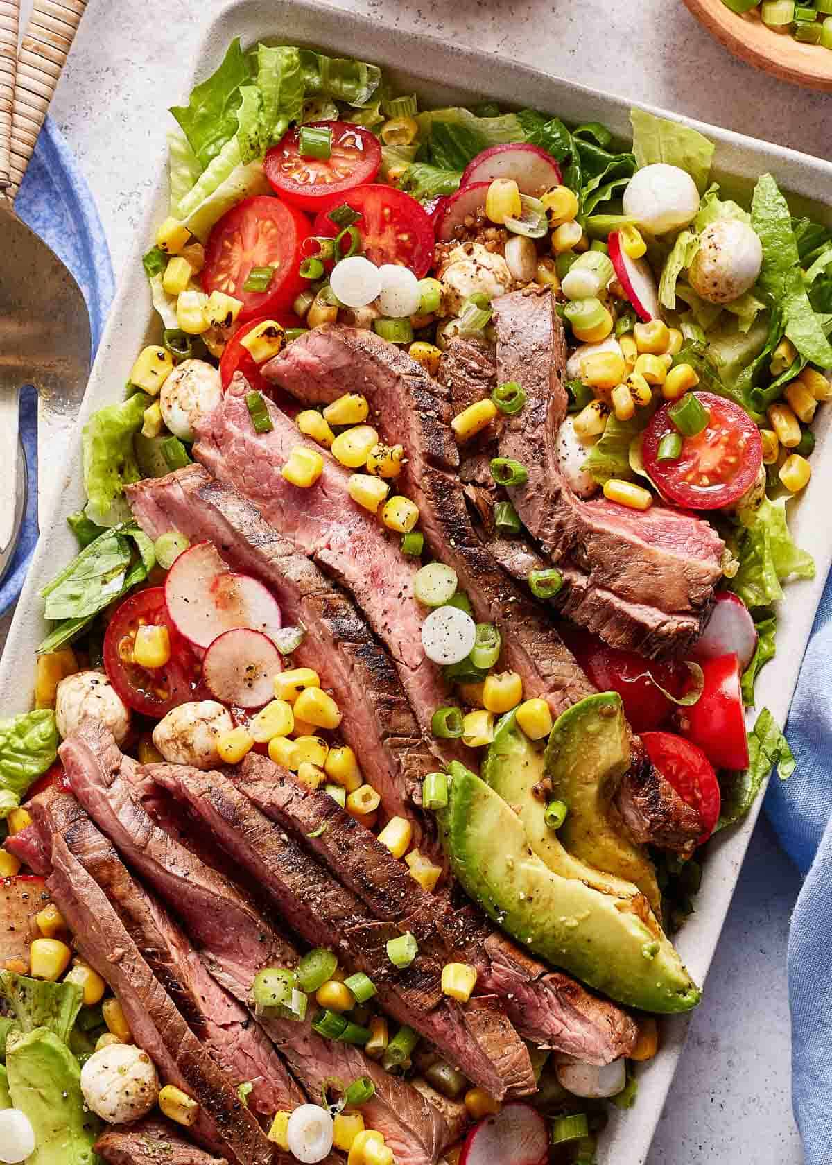 Grilled flank steak salad garnished with corn from the top view.