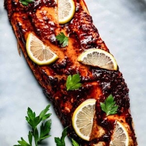 Harissa salmon fresh out of the oven garnished with lemon slices.