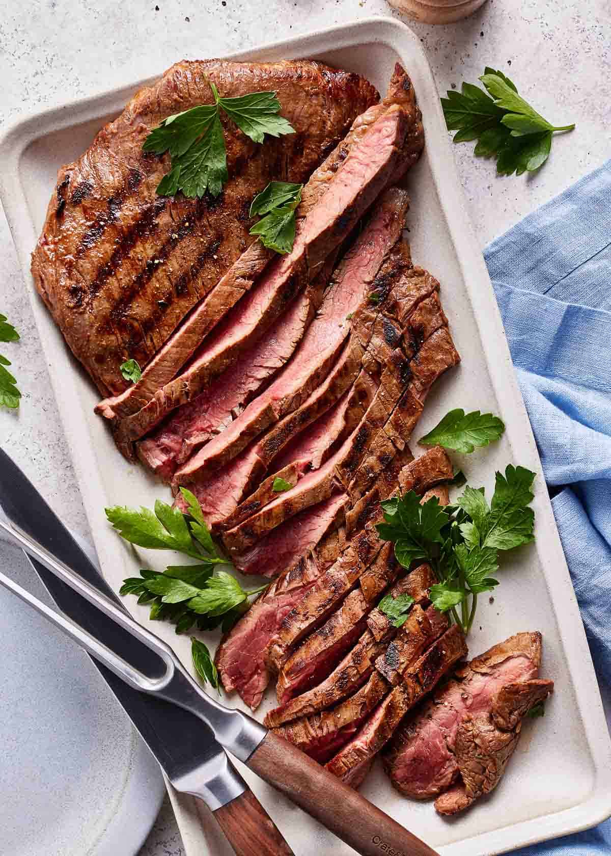 Marinated flank steak sliced on a plate.