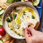 Person scooping whipped feta with pita bread.