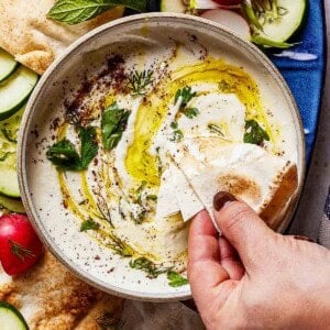 Person scooping whipped feta with pita bread.