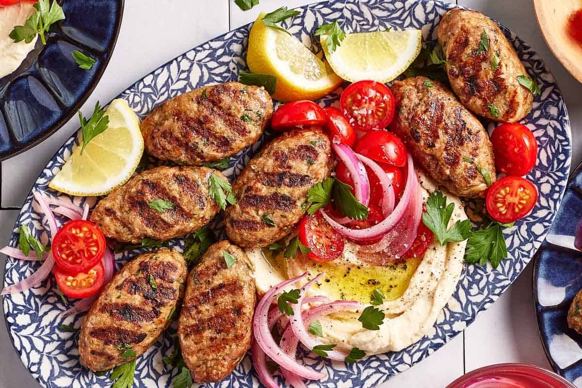 Grilled chicken kofta served with hummus, sliced onions and tomatoes.