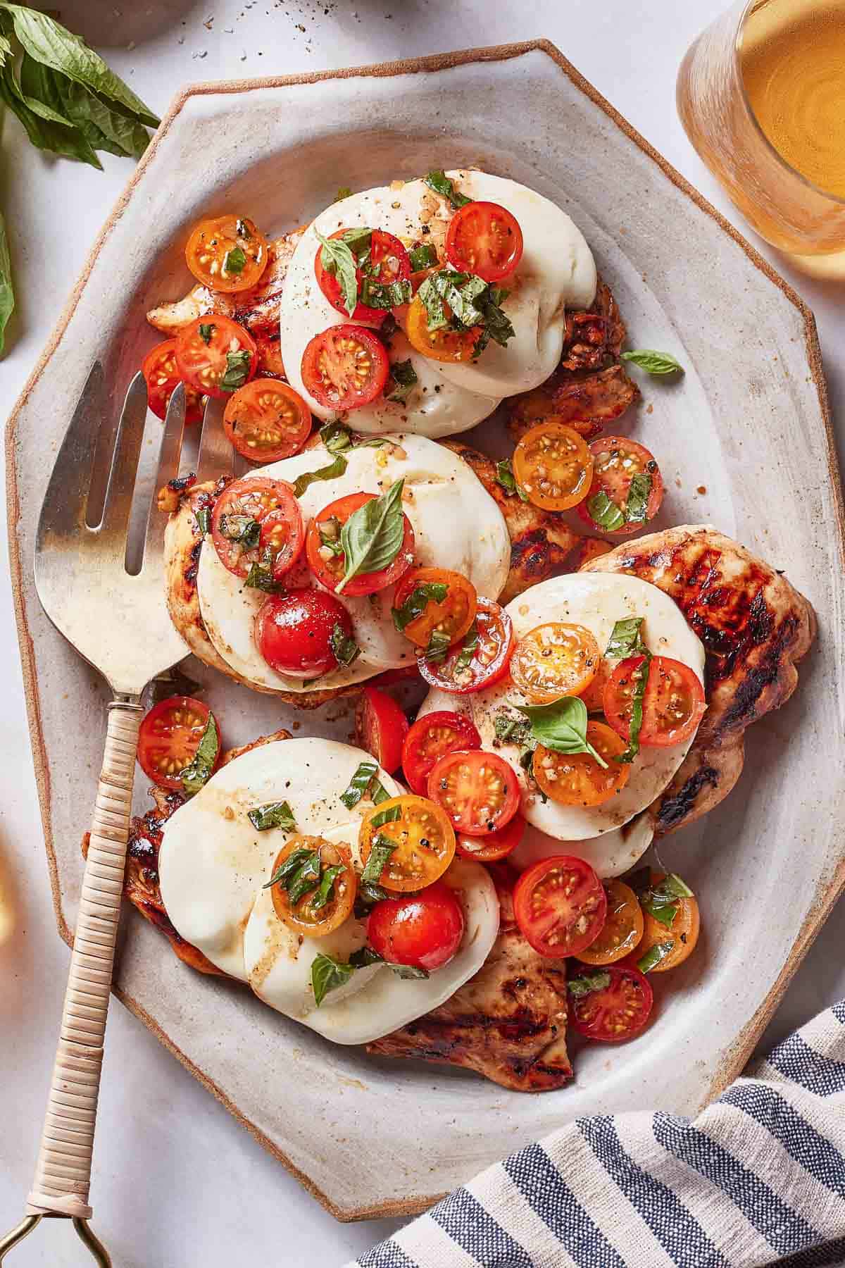 Grilled Caprese chicken on a plate garnished with basil.