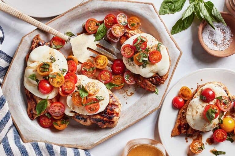Grilled Caprese chicken garnished with tomatoes on a plate.