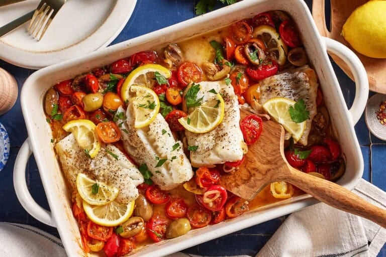 Baked cod with tomatoes and olives in a casserole dish.