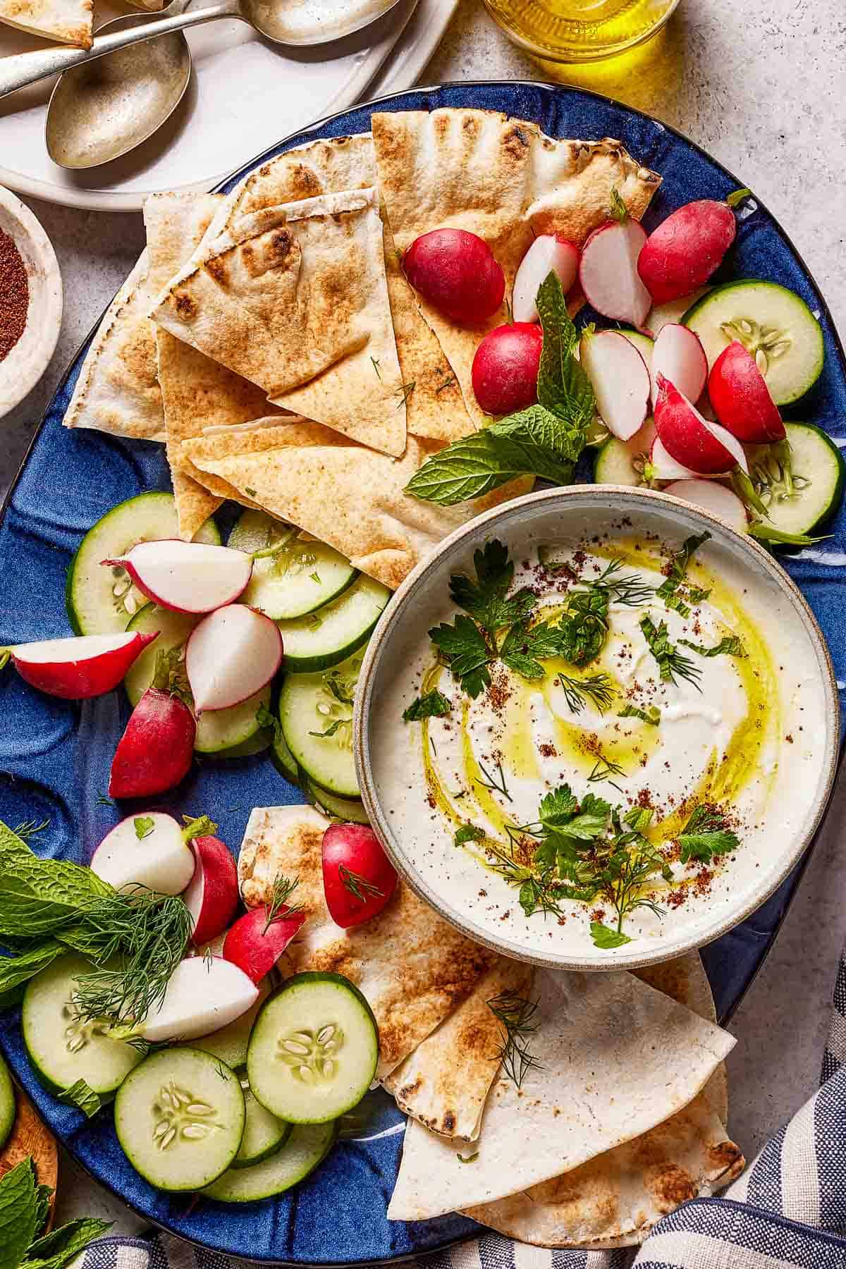 Whipped feta dip with vegetables and pita on a serving platter.