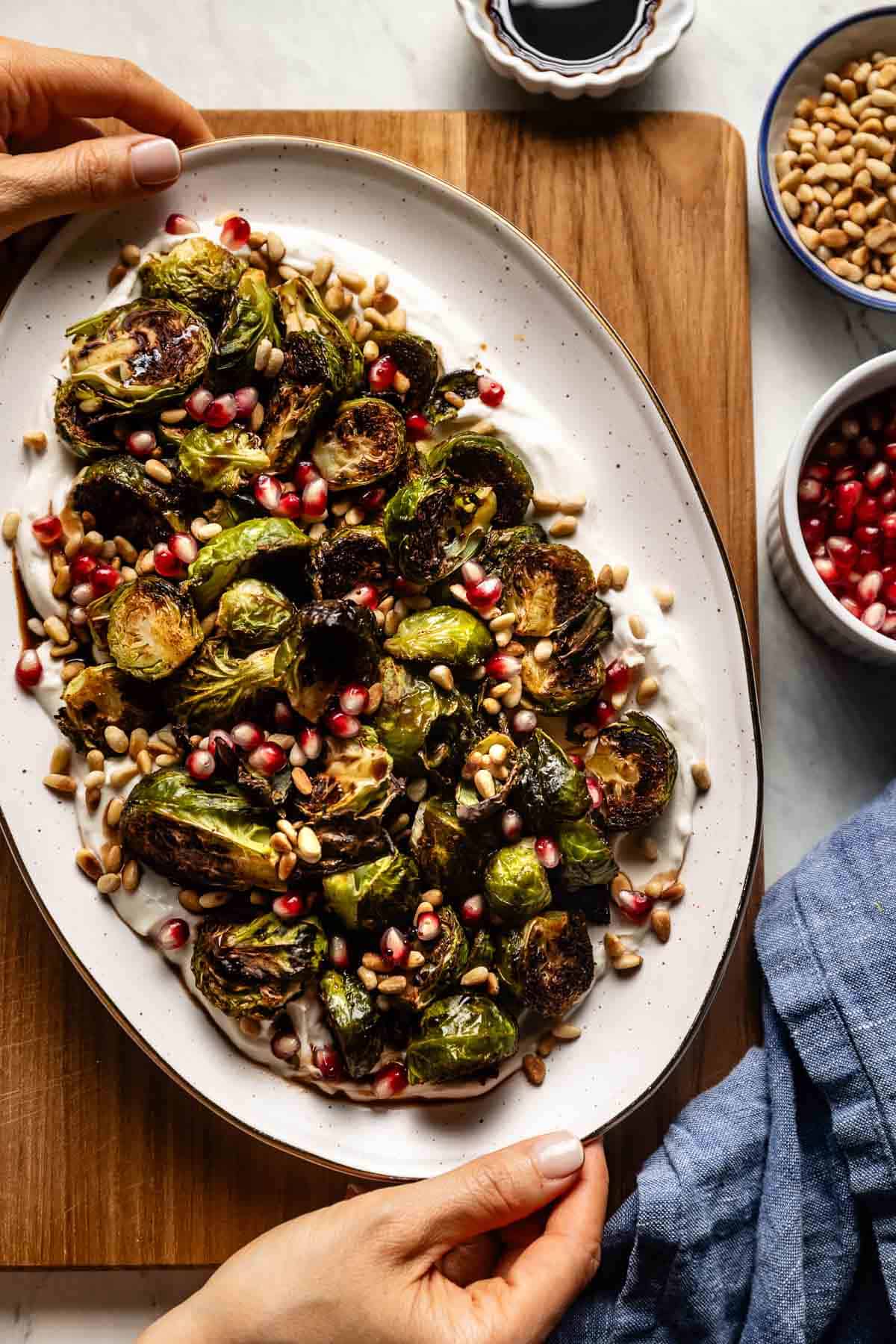 Roasted Brussel sprouts served over tahini yogurt sauce on a plate.