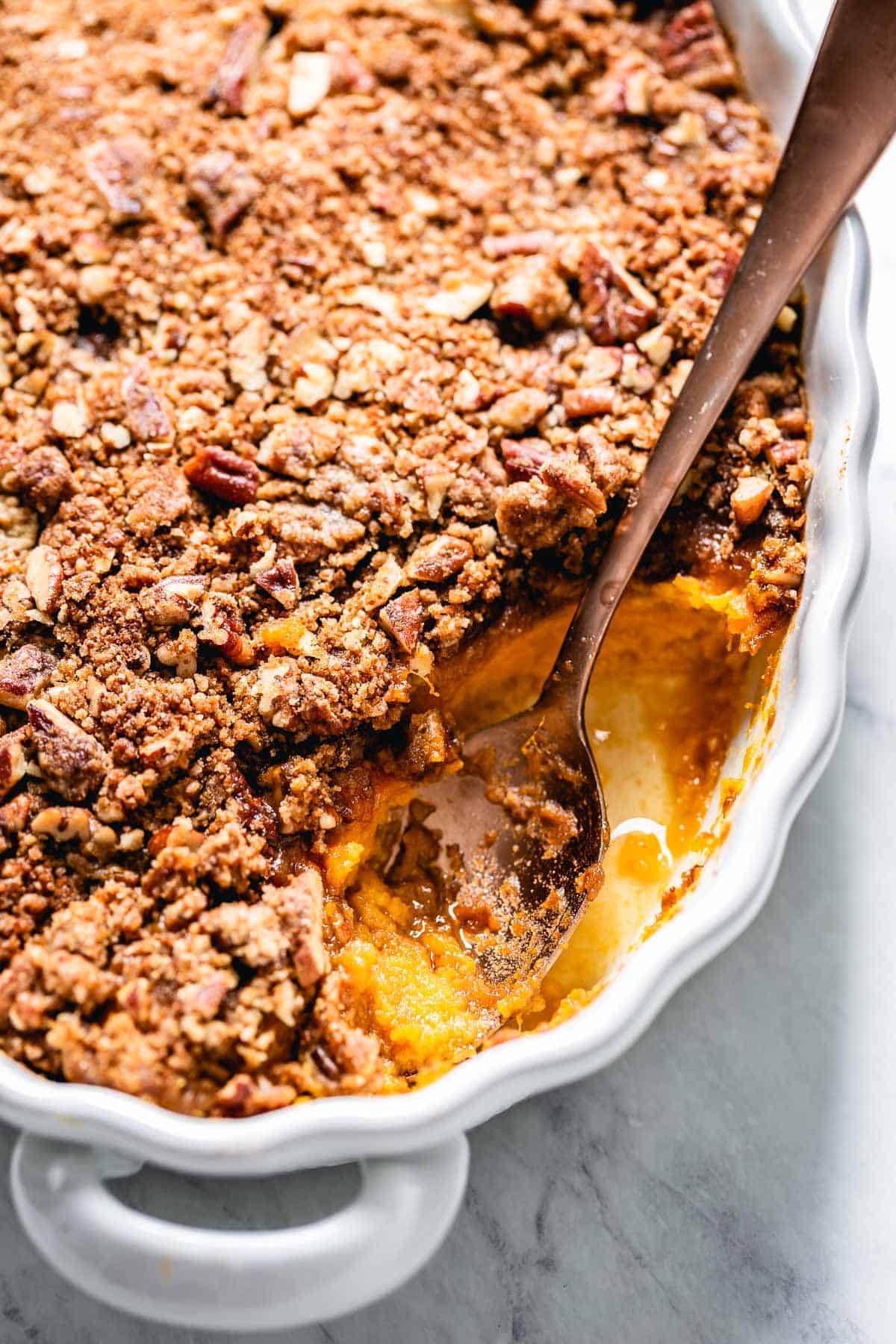 Sweet potato casserole with a spoon on the side of the casserole dish.