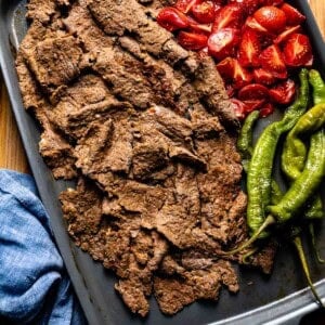 Doner kebab meat with roasted tomatoes and peppers on the side.