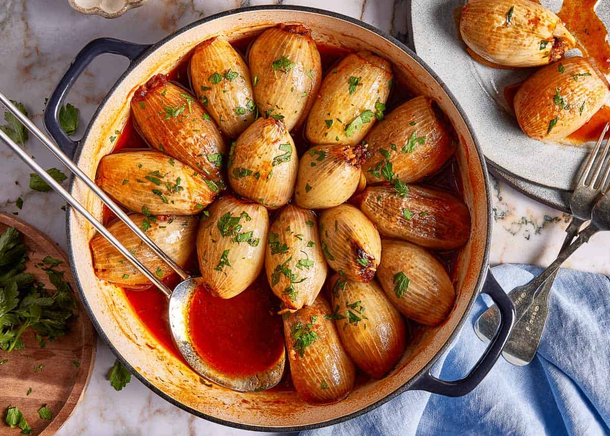 Ground beef stuffed onions in a skillet from the top view.
