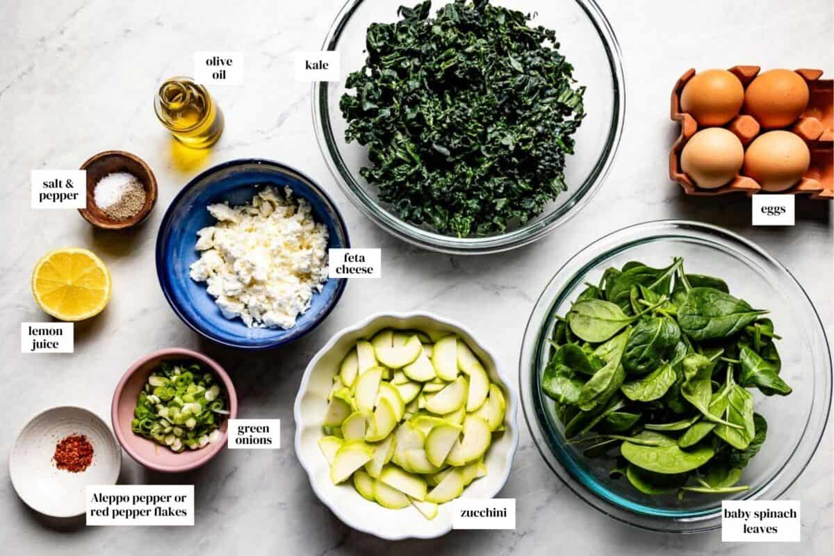 Ingredients for Green Shakshuka including kale, spinach, sliced zucchini, eggs, scallions, and Aleppo pepper.