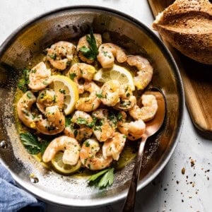 A skillet filled with juicy shrimp, lemon slices, and fresh parsley. This date night food is quick and easy to prepare.