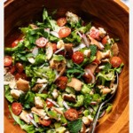 Fattoush salad in a wooden bowl with crispy pita, cherry tomatoes, radishes, and fresh herbs, with text reading "Fattoush Salad with my foolproof pita trick."