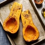 Freshly roasted butternut squash halves tender and slightly caramelized on a sheet pan from the top view.
